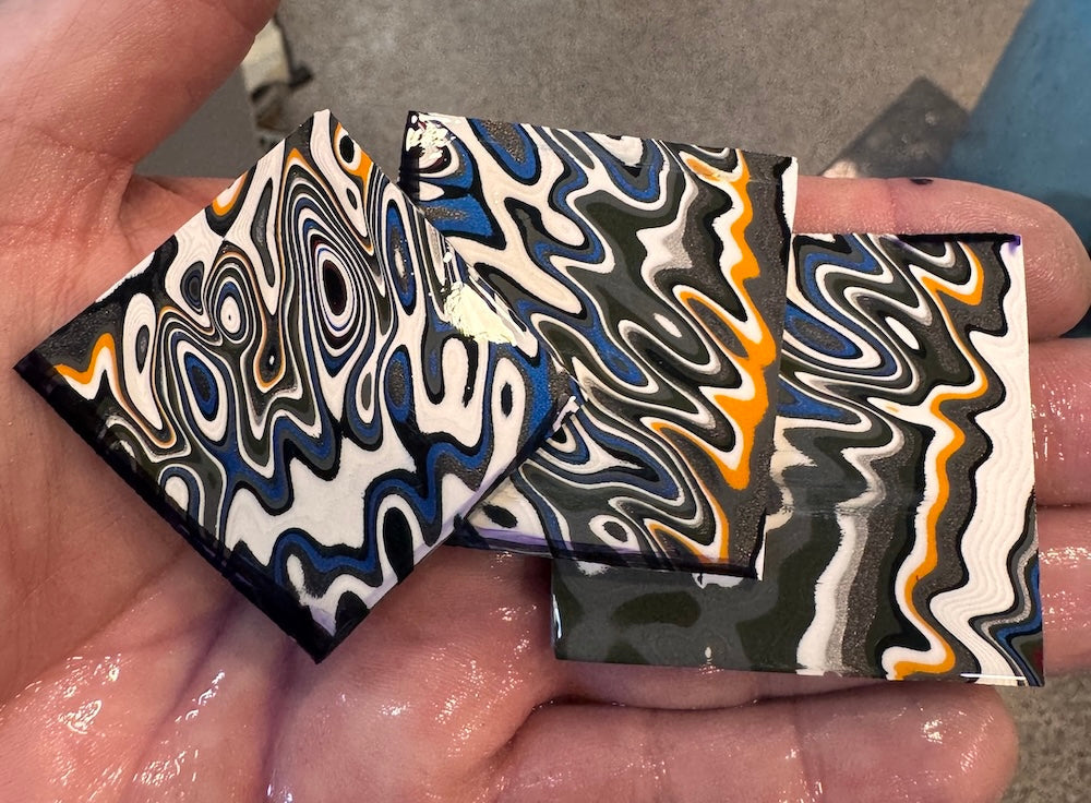 Three slices of unusually-coloured Fordite, showing yellows, whites, blacks, and a rare olive green.